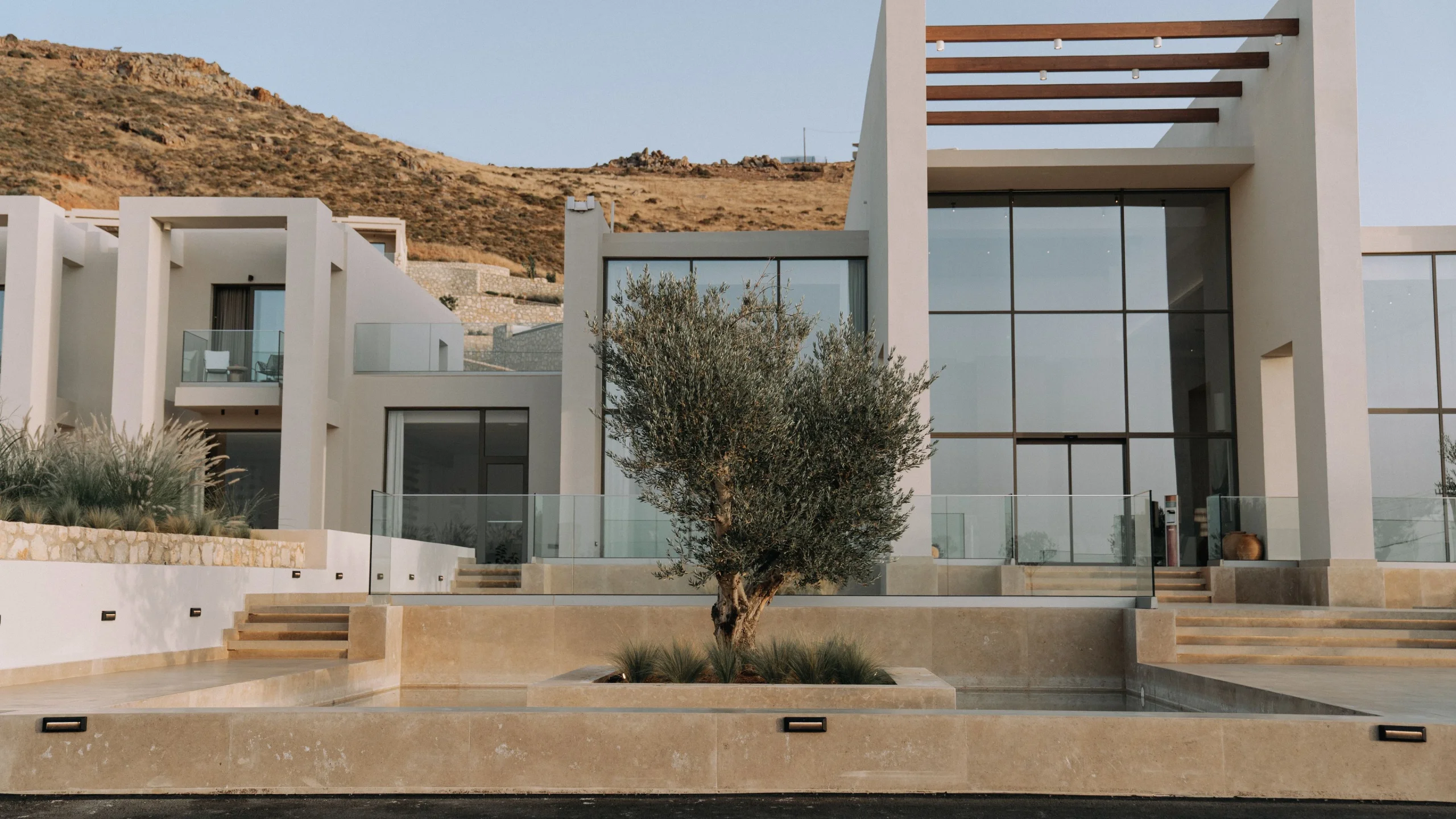 Contemporary luxury home with full-height glazing and a stone paved terrace in strong daylight
