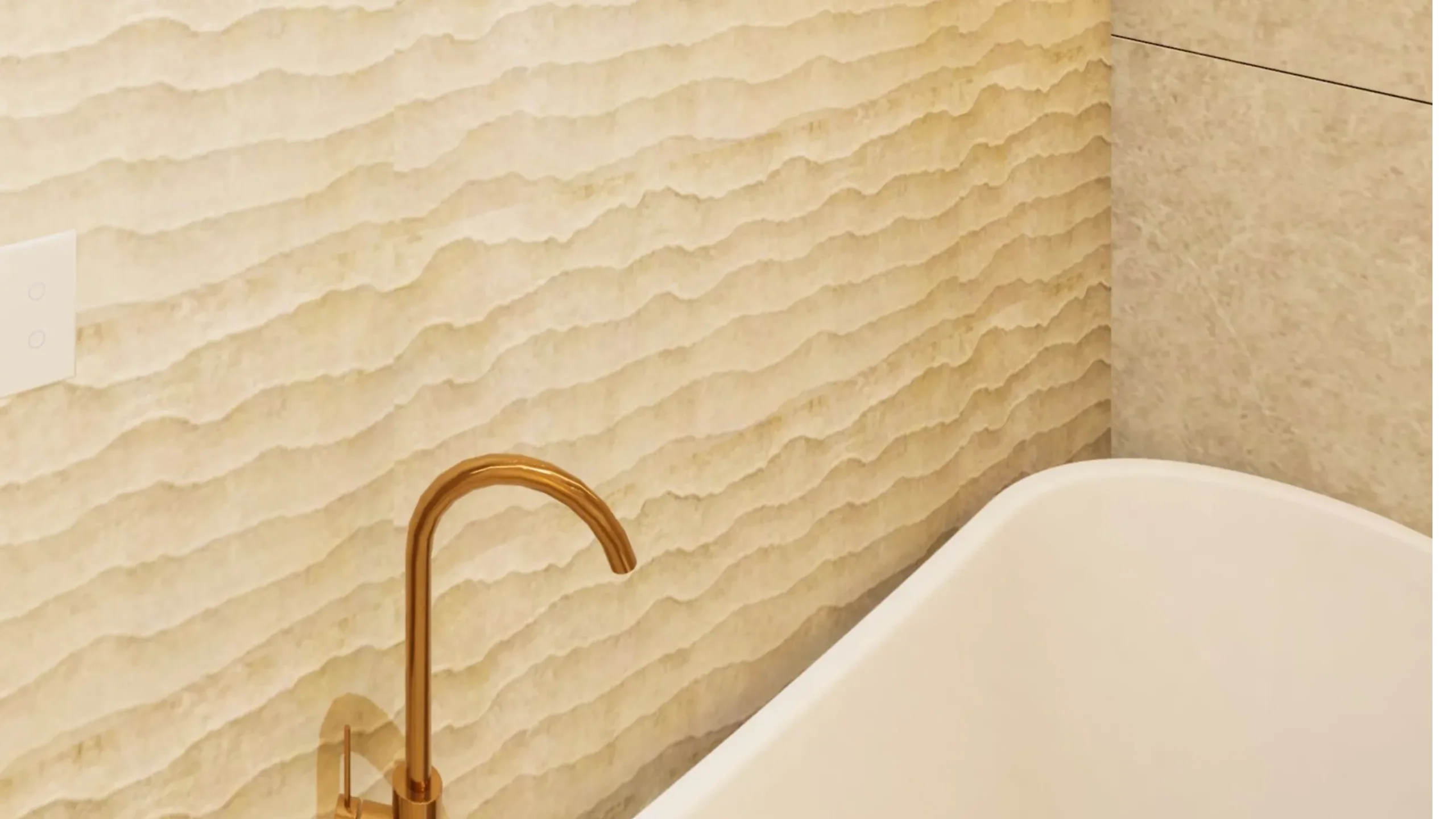 Freestanding bath with a floor mounted brass bath filler against a textured stone wall at Project 251