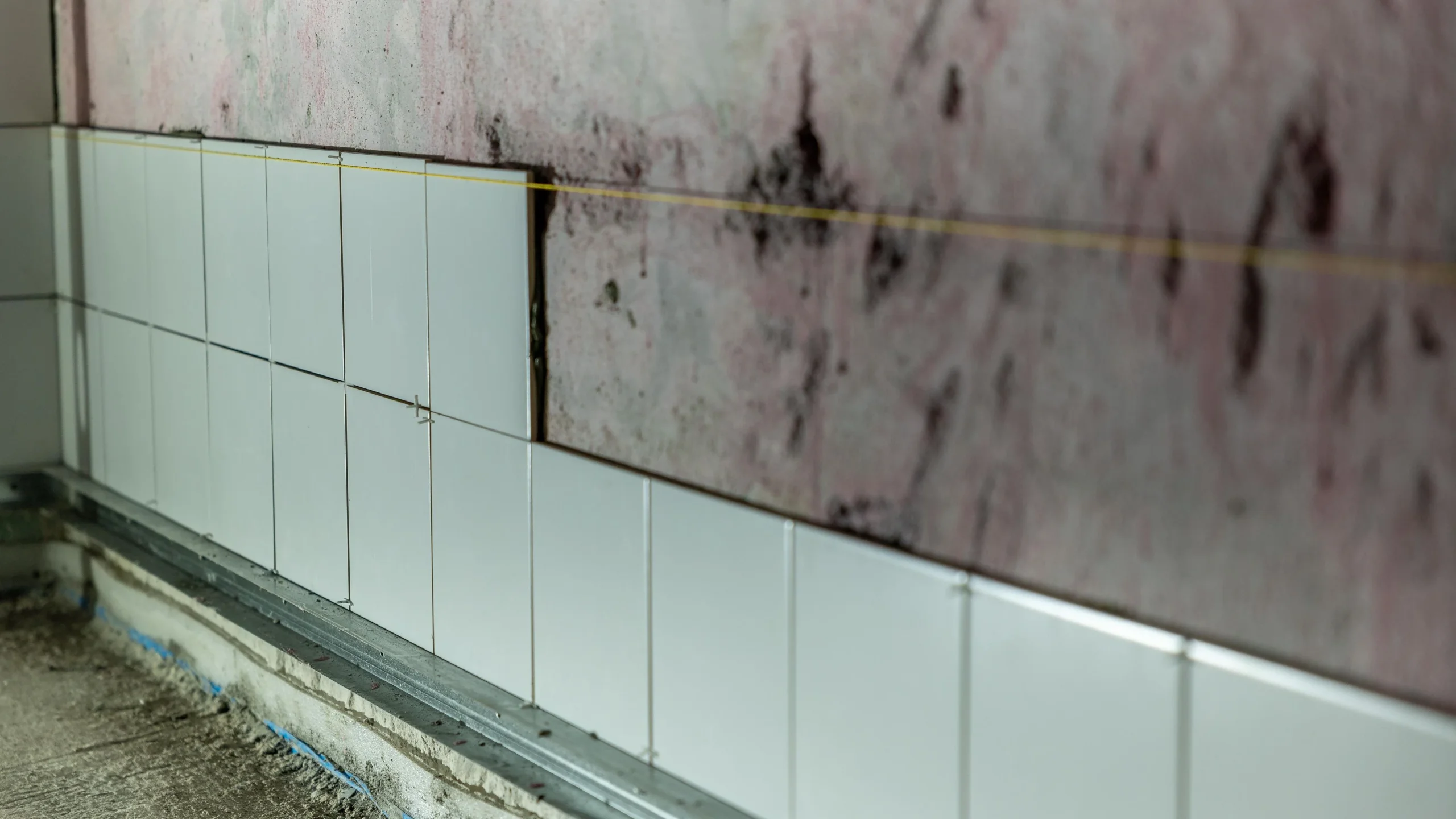 Wall tiles being laid over a waterproofing membrane during a bathroom fit out
