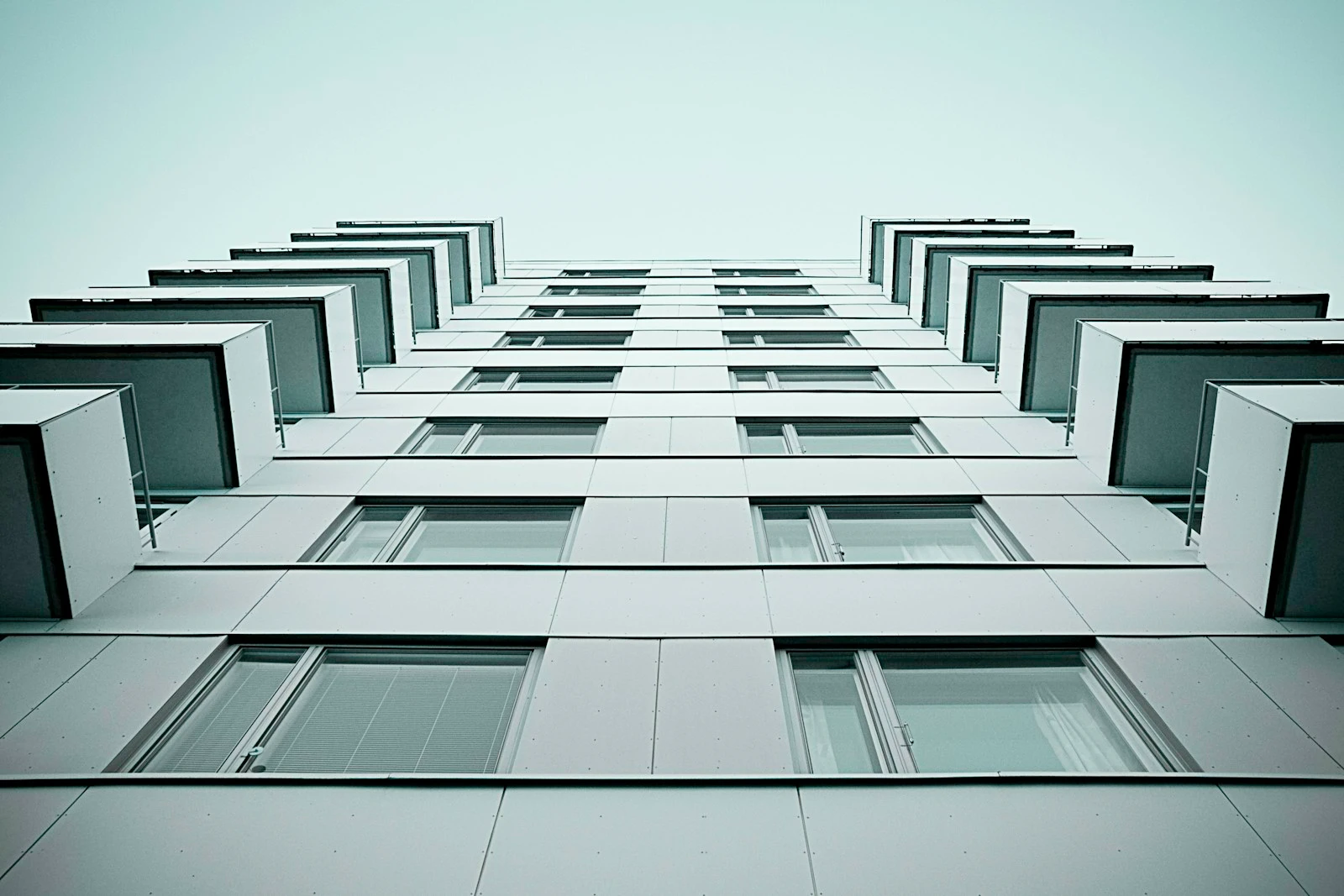 Looking up at the balconies of a white apartment building