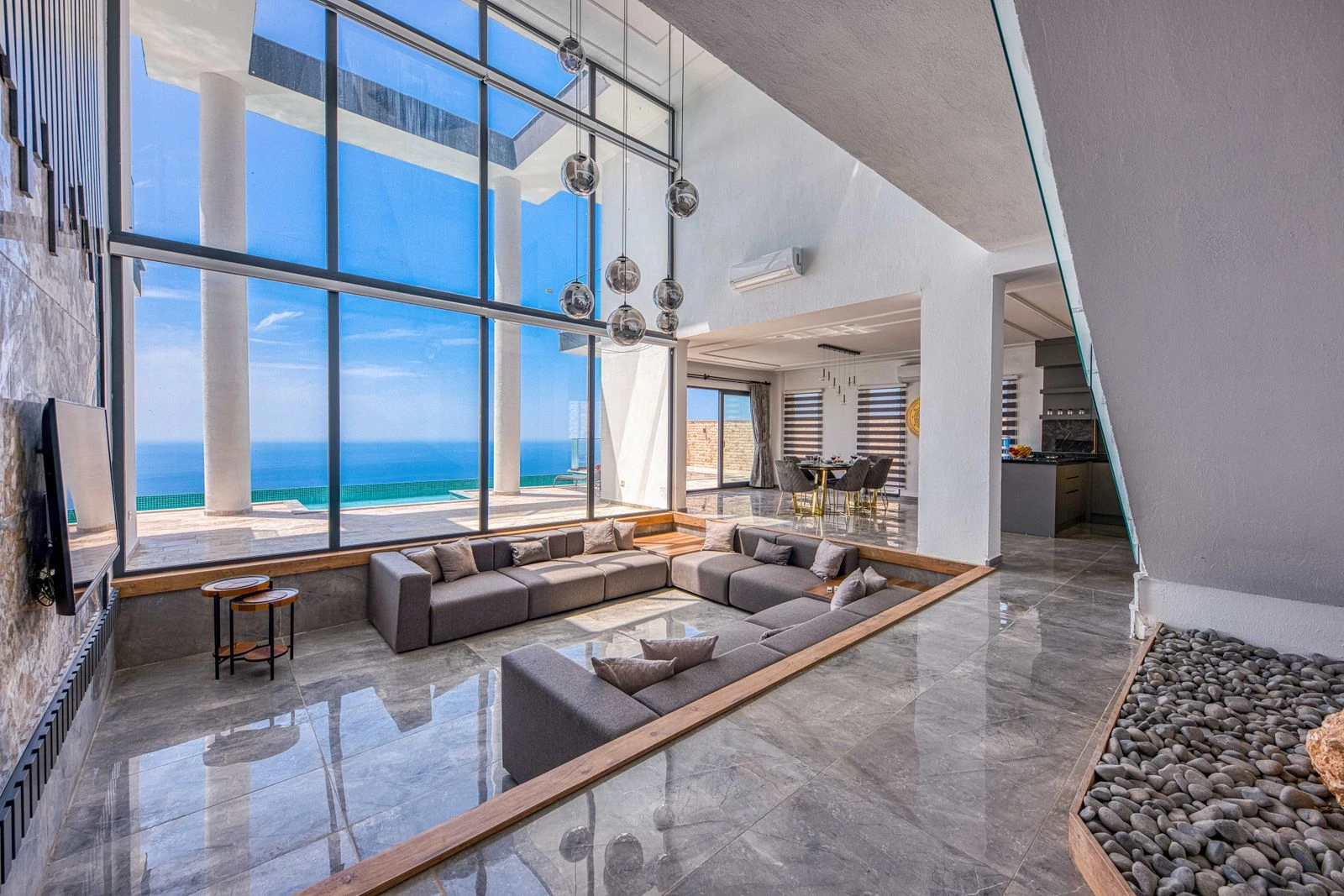 Double-height living room with a mezzanine and floor-to-ceiling glazing to the ocean