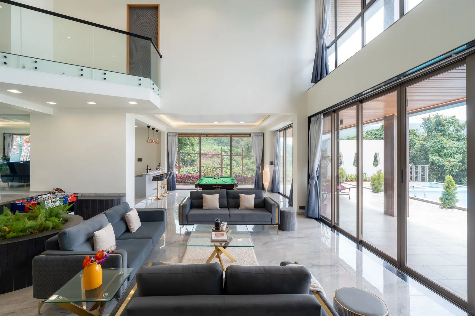 Open-plan living room with sliding glass walls opening to a garden and pool